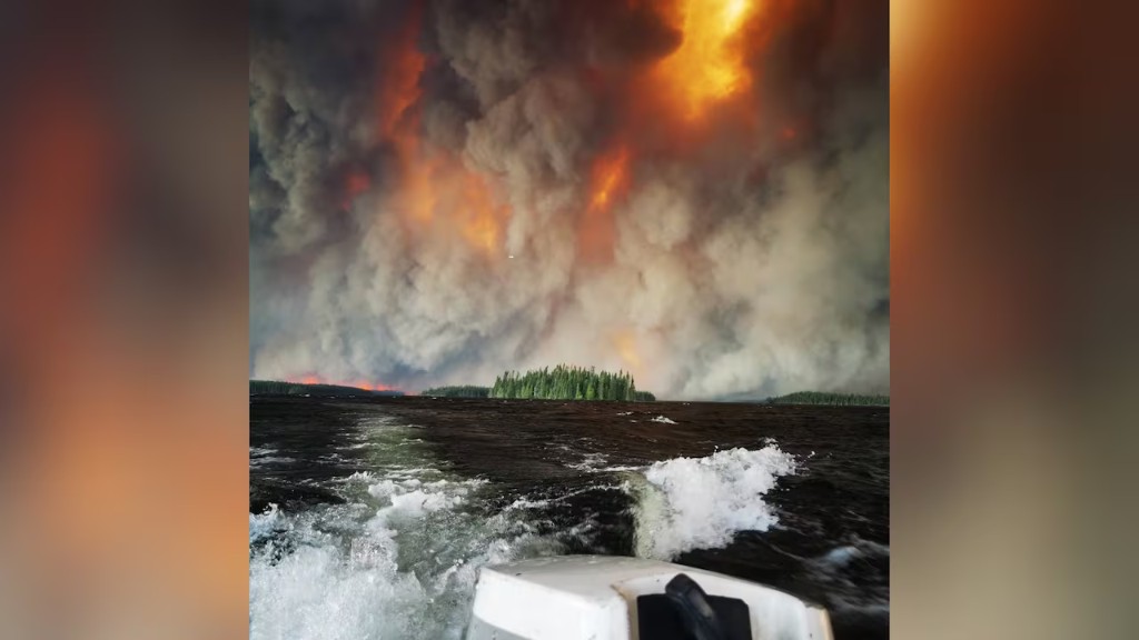 Wildfire smoke rising over a lake near Namaygoosisagagun First Nation
